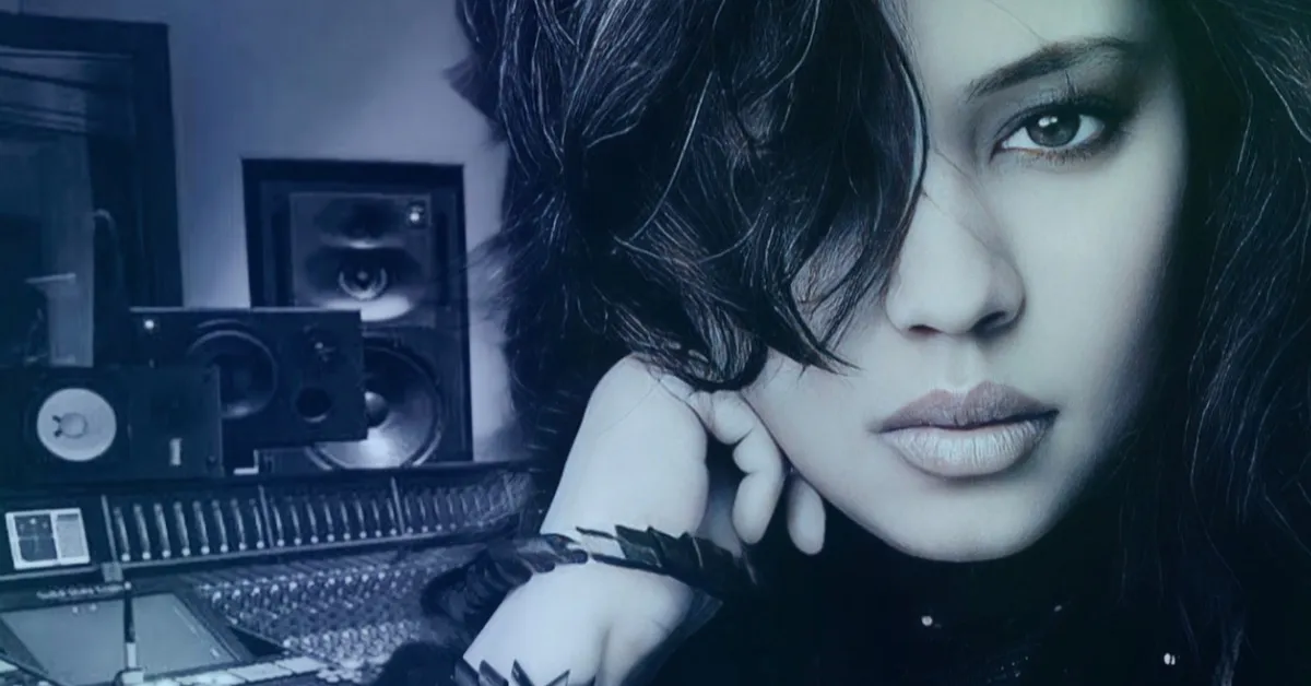 Anjalts resting her chin on her hand in the studio, monitor speakers and a mixing console behind