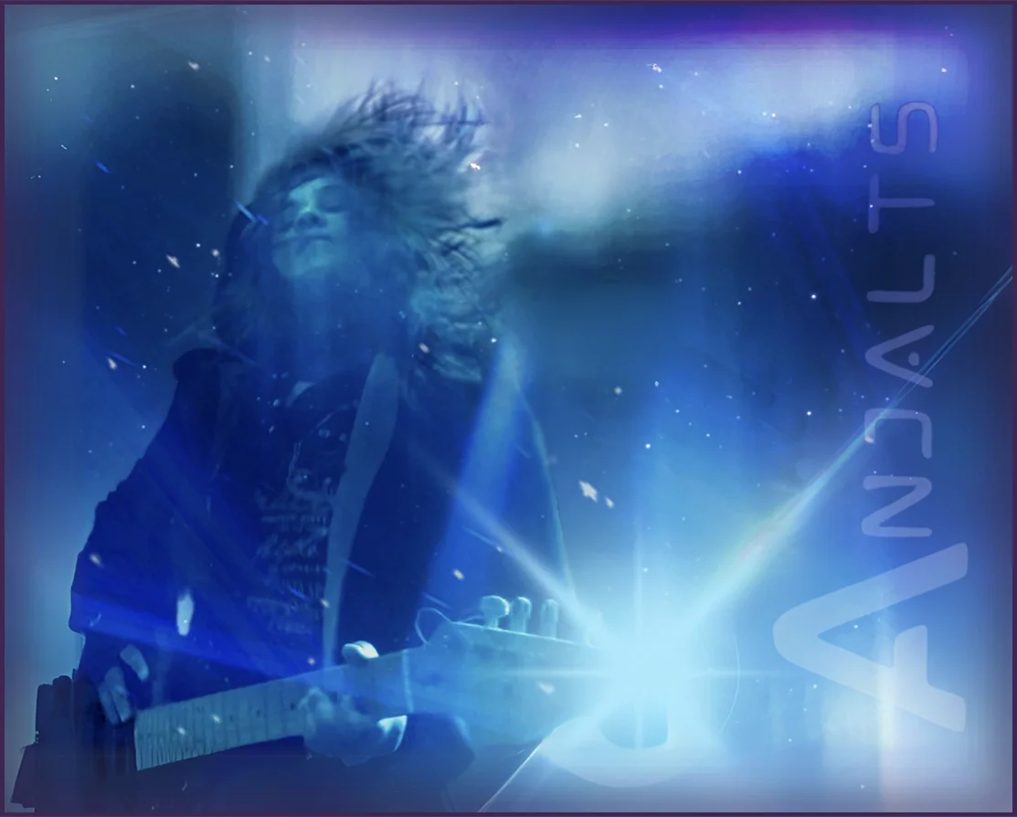 Anjalts playing electric guitar live, hair flying, lit blue by the stage lights