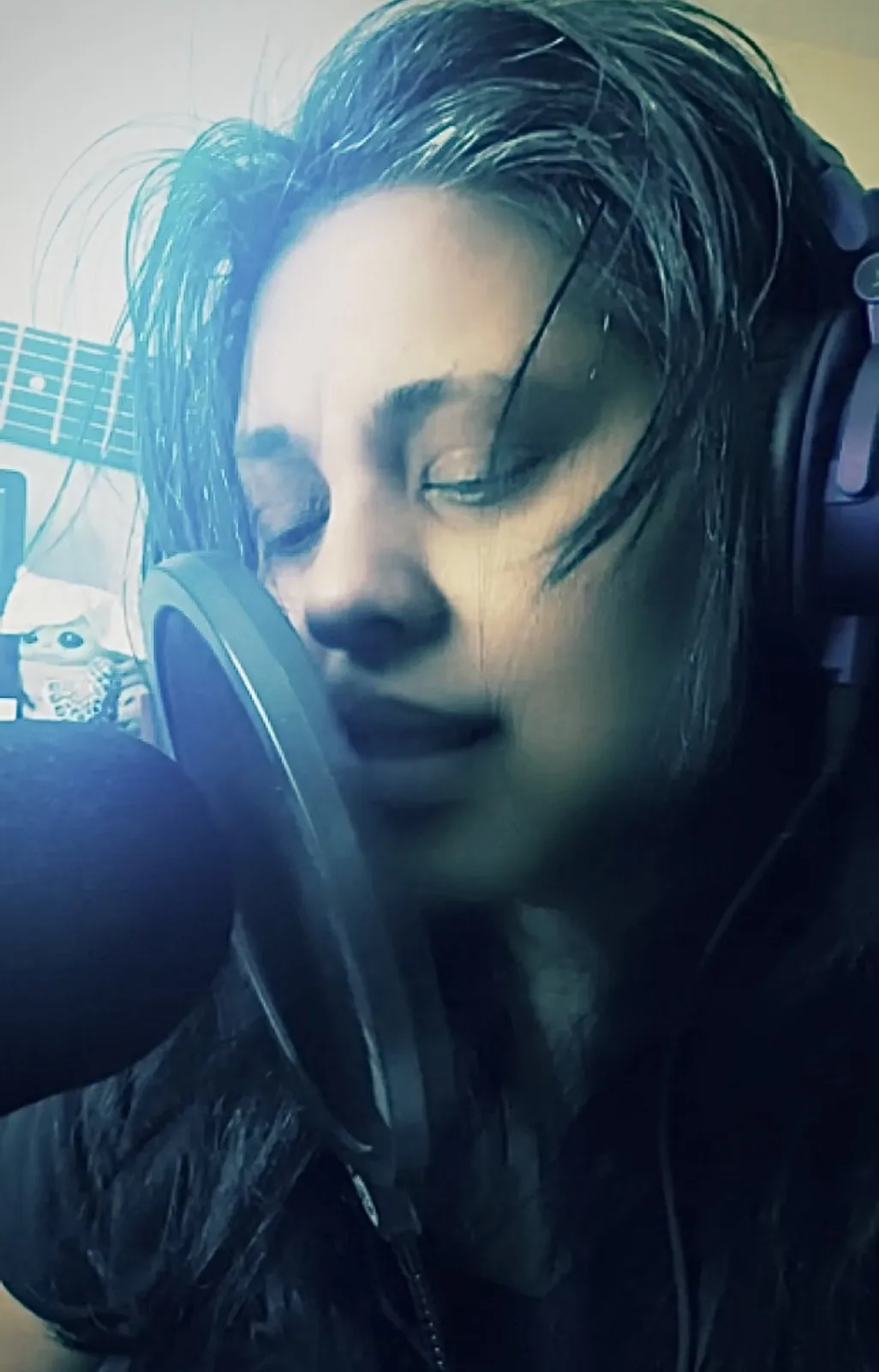 Anjalts singing into a studio microphone wearing headphones